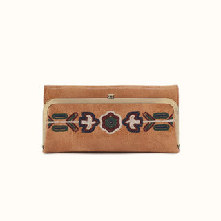 Front view of a light brown distressed leather rectangular wallet against a solid white background. The front features a prominent antique brass-tone metal kiss-lock frame that secures the main compartment. Spanning horizontally across the framed leather section is a vibrant, bohemian-inspired embroidered pattern. The intricate folk-art design features a central floral motif flanked by stylized birds and geometric arrows stitched in shades of navy blue, forest green, deep burgundy, and cream. The wallet com