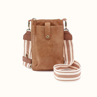 Front view of a brown leather crossbody phone bag against a solid white background. The compact, vertical bag features a distressed, textured leather finish with a front slip pocket secured by a leather tab and an antique brass snap button. It includes a secure top zipper closure with a long leather zipper pull. Attached by brass lobster clasps is a wide, detachable woven canvas strap featuring a cream and brown striped chevron pattern with brown leather trim accents.