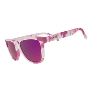 Angled side view of the Goodr "OMG, I Could Just Dye" sunglasses against a white background. This perspective highlights the continuous pink and white tie-dye pattern extending seamlessly down the temple arms. The classic "goodr" logo is embedded in metallic text on the temple arm, while the curved reflective magenta lenses complete the playful, retro-inspired aesthetic.