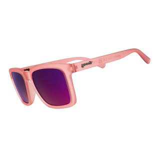 Angled side view of the Tropical Hibiscus Tea Party sunglasses. This perspective highlights the continuous matte light pink finish across the front frame and temple arms. The classic "goodr" logo is embedded in contrasting dark metallic text on the temple arm, while the vibrant pink and purple reflective lenses complete the bold, tropical aesthetic.