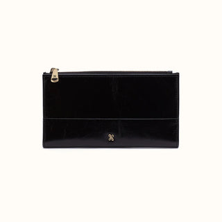Front view of a sleek, black leather rectangular wallet against a solid white background. The wallet features a polished, lightly crinkled leather texture with a horizontal stitched seam detail running across the lower third of the front face. It includes a secure top zipper closure equipped with a gold-tone metal zipper pull engraved with the HOBO brand logo. A matching, small gold-tone HOBO emblem is centered near the bottom edge, adding a subtle touch of signature hardware to the minimalist design.