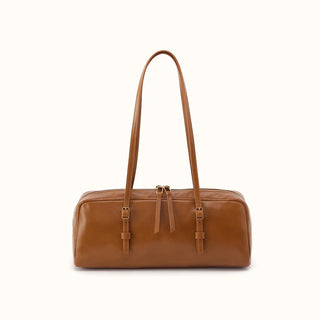 Front view of a smooth, truffle brown leather shoulder bag featuring a trendy, elongated East-West silhouette. The structured, minimalist design highlights two long, slender shoulder straps attached directly to the front panel with small, adjustable gold-tone buckles and leather keeper loops. The top features a functional dual-zipper closure complete with long, matching leather pull tabs for easy access, all presented against a crisp white studio background.