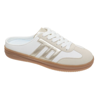 Side-angled studio view of a women's retro-inspired slip-on sneaker mule featuring a crisp white leather upper, soft beige suede T-toe overlay, and metallic champagne-gold side stripes. Designed with a low-profile gum rubber sole, white lace-up closure, and an open backless silhouette for easy slip-on wear, set against a clean white background.